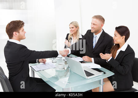 Partenaires d'affaires shaking hands at desk in office Banque D'Images