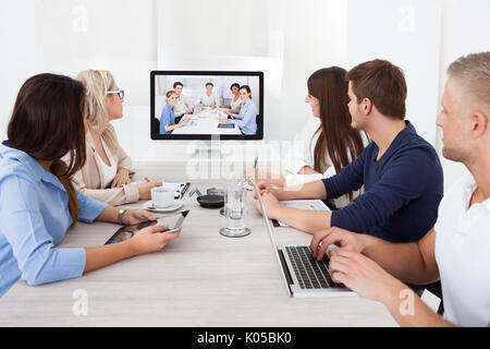 L'équipe d'assister à la conférence vidéo at desk in office Banque D'Images