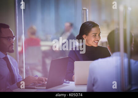 Smiling businesswoman at laptop l'écoute dans la salle de conférence réunion Banque D'Images