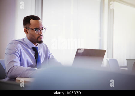 Serious businessman using laptop in conference room Banque D'Images