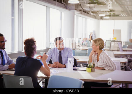 Business people talking at table in shared workspace Banque D'Images