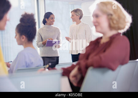 Businesswomen talking in conference audience Banque D'Images