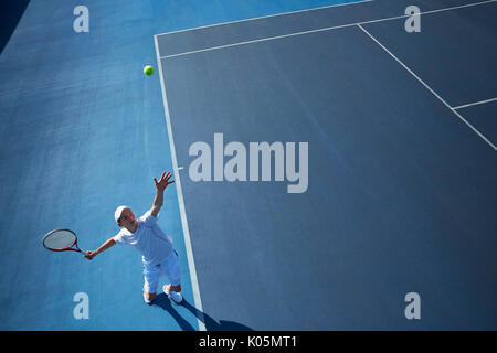 Vue aérienne du jeune joueur de tennis masculin en jouant au tennis, au service de la balle de tennis sur sunny blue