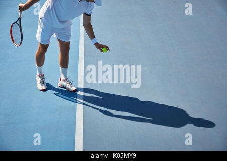 Jeune joueur de tennis masculin en jouant au tennis, balle de tennis qui rebondit sur sunny blue tennis Banque D'Images