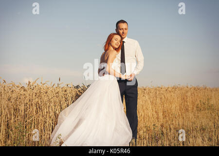 Magnifique mariée et le marié en champ de blé. Le bonheur et le mariage. Femme en robe blanche homme en chemise blanche et cravate serrant les uns les autres. Banque D'Images
