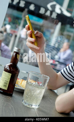 Les jeunes mâles adolescents using mobile phone in cafe Banque D'Images