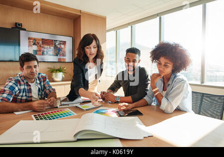 Les gens créatifs à projet au plan établi sur la table. Mixed Race associés discutent de nouvelles plan de projet dans un bureau moderne. Banque D'Images
