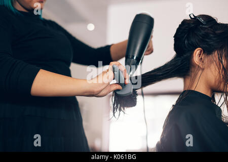 Coiffure féminine à l'aide de la soufflante et brosse pour cheveux secs. Salon de beauté à l'aide de cheveux femme sur cheveux mouillés dans le salon. Banque D'Images