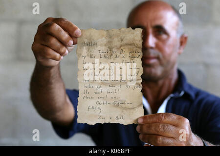 La ville de Gaza, bande de Gaza, territoire palestinien. Août 21, 2017. Pêcheur palestinien Jihad al-Soltan affiche un message qui a été écrit par Wright et son petit ami Zac Marriner, après qu'il l'a trouvé dans une bouteille sur une plage de Gaza, à Gaza, le 21 août 2017 Credit : Yasser Qudih/APA/Images/fil ZUMA Alamy Live News Banque D'Images