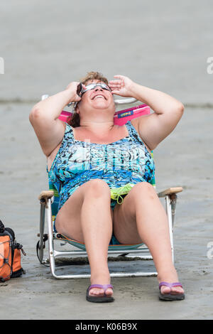 Charleston, Isle of Palms, USA. Août 21, 2017. Une femme se détend dans une chaise de plage comme elle l'éclipse totale de la vue sur la plage à l'extérieur de Charleston, 21 août 2017 à Isle of Palms, Caroline du Sud. L'éclipse solaire, après avoir balayé tout le pays traverse la région de Charleston avant de partir sur l'océan Atlantique. Credit : Planetpix/Alamy Live News Banque D'Images