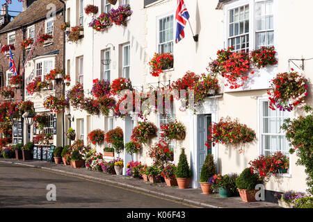 Rangée de maisons de style régence principalement blanc, vers 1800, et l'édifice de brique, King's Head pub à la fin de la lumière du soleil tôt le matin avec affichage floral de fleurs rouges principalement. Union Jack pend de l'avant de la façade double chambre. Banque D'Images