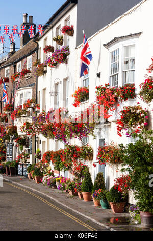 Rangée de maisons de style régence principalement blanc, vers 1800, et l'édifice de brique, King's Head pub à la fin de la lumière du soleil tôt le matin avec affichage floral de fleurs rouges principalement. Union Jack pend de l'avant de la façade double chambre. Banque D'Images