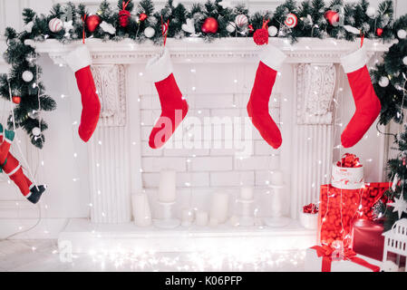 Près d'une photo de Noël rouge vif magnifiquement décorée chaussettes suspendu par une cheminée en attente de présente. Banque D'Images