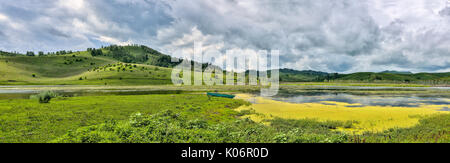 Lac incroyable dans vallée de montagnes avec des algues et de lis blancs couverts - Vue panoramique du paysage d'été avec ciel nuageux et bateau sur la rive de l'étang, un Banque D'Images