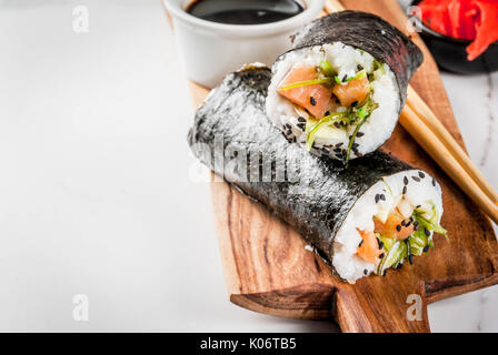 L'alimentation hybride de tendance. Le japonais, la cuisine asiatique. Burrito à sushi, sandwich au saumon, Hayashi, daikon wakame, gingembre mariné, caviar rouge. Sur un marbre blanc Banque D'Images