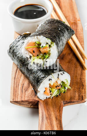 L'alimentation hybride de tendance. Le japonais, la cuisine asiatique. Burrito à sushi, sandwich au saumon, Hayashi, daikon wakame, gingembre mariné, caviar rouge. Sur un marbre blanc Banque D'Images