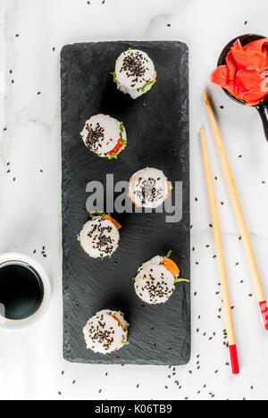 L'alimentation hybride de tendance. Japanese cuisine asiatique. Sushi Mini-hamburgers, sandwiches au saumon, wakame hayashi, daikon, gingembre, caviar rouge. Table en marbre blanc, Banque D'Images