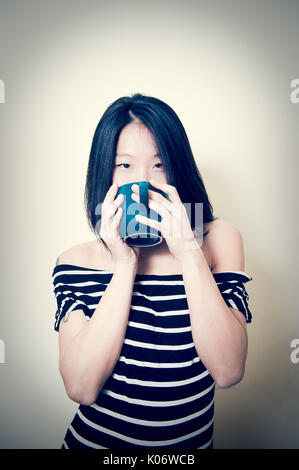 Belle jeune femme asiatique heureux à la caméra en mode portrait avec blue Petroleum mug sur sa bouche Banque D'Images