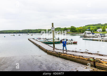 Damariscotta, USA - 9 juin 2017 : Femme avec parapluie marche sur la jetée du port de plaisance dans petit village dans le Maine pendant la pluie avec des bateaux Banque D'Images