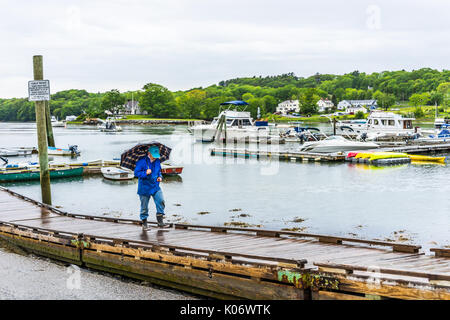 Damariscotta, USA - 9 juin 2017 : Femme avec parapluie marche sur la jetée du port de plaisance dans petit village dans le Maine pendant la pluie avec des bateaux Banque D'Images