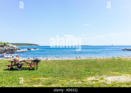 Cape Elizabeth, USA - 10 juin 2017 : Des gens assis sur des tables de pique-nique sur la plage publique appelée Ship Cove par Portland Head Lighthouse dans le Maine Banque D'Images