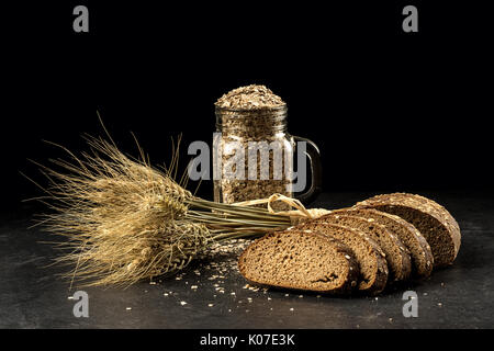 Bouquet de grain, l'avoine d'or en épillets jar sur table en bois foncé, petits pains et pouvez remplis de grains secs. la nourriture, concept boulangerie Banque D'Images