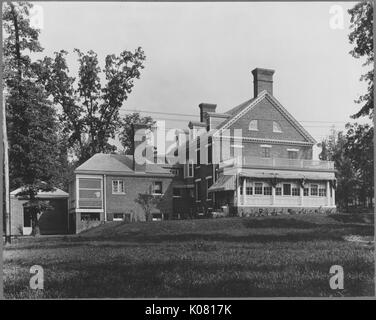 Photographie de la côté d'un parc qui est Roland maison de trois étages, en brique et deux balcons, avec de grandes fenêtres de verre, entouré d'arbres en plus d'un champ herbeux, United States, 1920. Cette image est tirée d'une série sur la construction et la vente de maisons dans le quartier Roland Park/Guilford de Baltimore, a streetcar suburb et l'une des premières communautés planifiées aux États-Unis. Banque D'Images