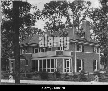 Photographie d'un grand parc Roland trois étages maison, faite de briques avec de grandes fenêtres de verre, situé derrière une petite clôture de barbelés, entouré de nombreux arbres, United States, 1920. Cette image est tirée d'une série sur la construction et la vente de maisons dans le quartier Roland Park/Guilford de Baltimore, a streetcar suburb et l'une des premières communautés planifiées aux États-Unis. Banque D'Images