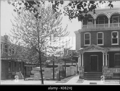 Vue de façade de maison à étages avec fondation en pierre sur rue calme, zone de construction à gauche, plusieurs fenêtres, une porte, des mesures et des colonnes montrant, porche balustrade au 3 ème étage, à côté d'arbre, Baltimore, Maryland, 1910. Cette image est tirée d'une série sur la construction et la vente de maisons dans le quartier Roland Park/Guilford de Baltimore, a streetcar suburb et l'une des premières communautés planifiées aux États-Unis. Banque D'Images