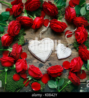 Roses rouges et deux coeurs sur fond de bois. Banque D'Images