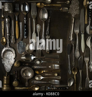 Coutellerie, fourchettes, cuillères, couteaux et sur fond de bois foncé Banque D'Images