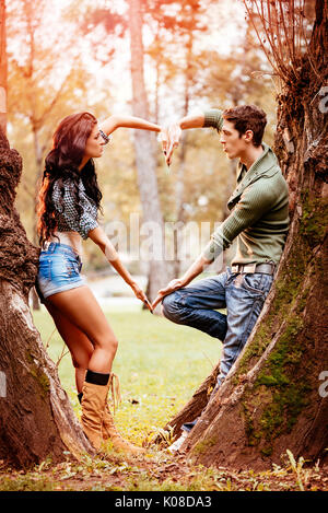 Belle lovely couple enjoying in sunny park en couleurs de l'automne et avec leurs mains en forme de coeur. Banque D'Images