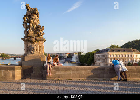 Une statue et quelques touristes au pont Charles (Karluv Most) à Prague, République tchèque, en début de soirée. Banque D'Images