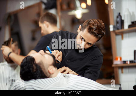 Jeune homme rasage coiffure concentré Banque D'Images