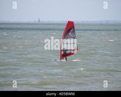 Un surfeur vent voiles sur le solent et l'île de Wight en arrière-plan. Banque D'Images