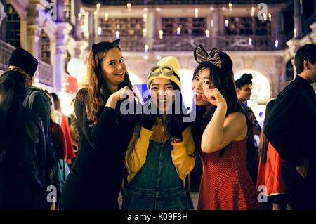 Trois étudiants en costume posent pour une photo, la jeune fille à l'extrême gauche est habillé comme un chat noir, la fille du milieu est habillé comme un favori du film 'Despicable Me' et la jeune fille à l'extrême droite porte une robe rouge et d'un bow noir sur sa tête, 2016. Banque D'Images