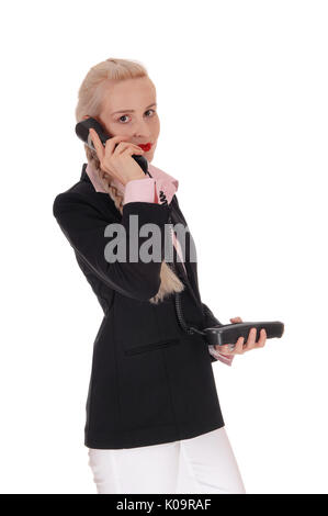 Une belle femme d'affaires dans une veste noire et chemisier rose longueurs de moitié debout, parler au téléphone, isolés pour fond blanc Banque D'Images