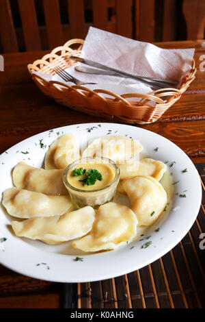 Plat vareniki russes et ukrainiennes avec une purée de pommes de terre et la crème fraîche et champignons sur plaque blanche. Close up. Banque D'Images