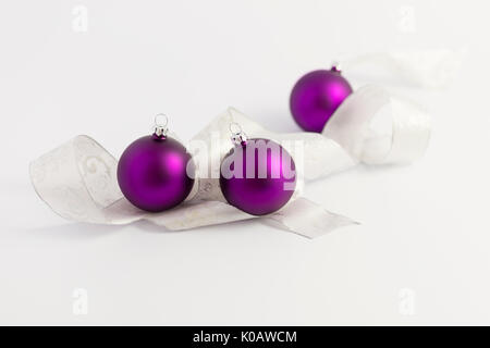 Belle pourpre brillant avec des boules de Noël blanc et argent ruban sur fond blanc Banque D'Images