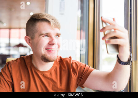 La technologie, la communication et les gens concept - Young man holding smartphone Banque D'Images