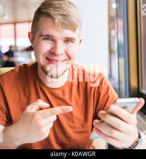 La technologie, la communication et les gens concept - Young man holding smartphone Banque D'Images