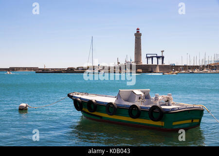 Un bateau avec des pneus et une bouée avec le Phare Le phare du Môle Saint-Louis dans l'arrière-plan. Sete, France Banque D'Images
