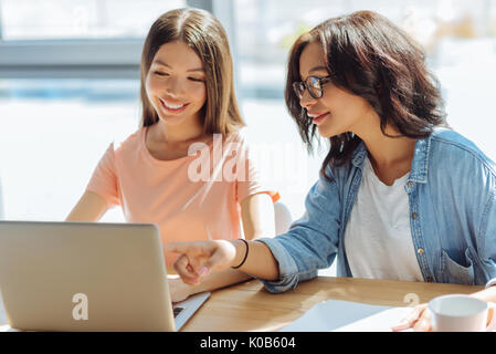 Belle femme agréable pointant sur l'écran d'ordinateurs portables Banque D'Images