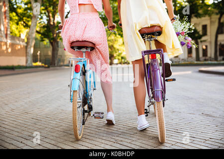 Vue arrière de deux filles en plein air vélos vintage équitation robes Banque D'Images