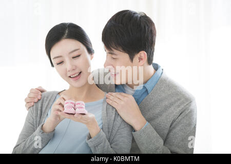 Portrait of pregnant couple harmonieux avec fournitures pour bébés Banque D'Images