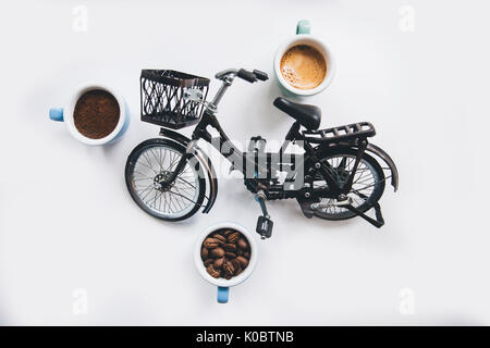 Les grains de café, expresso frais et du café fraîchement moulu avec un magnifique tigre épais crema et un vélo miniature sur le fond blanc Banque D'Images