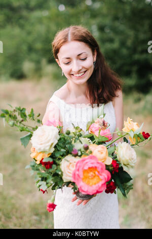 Bouquet, arrangement floral et concept - jeune femme avec un sourire au bouquet de pivoines rose, blanc et jaune, roses, œillets et estrade Banque D'Images