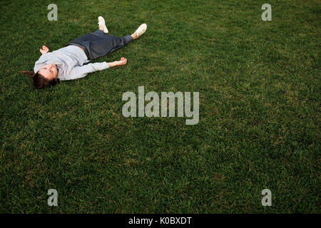 Belle jeune femme s'allonge sur l'herbe et repose Banque D'Images