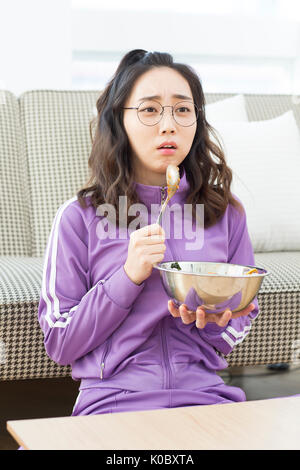 Les jeunes NEET femme regardant la TV eating meal Banque D'Images