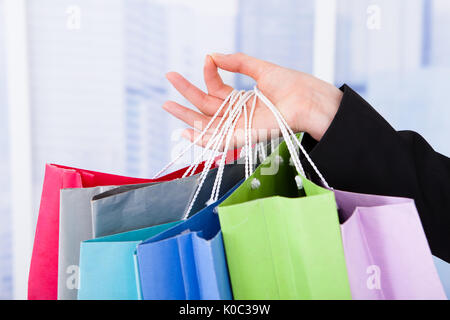 Portrait of businesswoman carrying shopping bags at office Banque D'Images